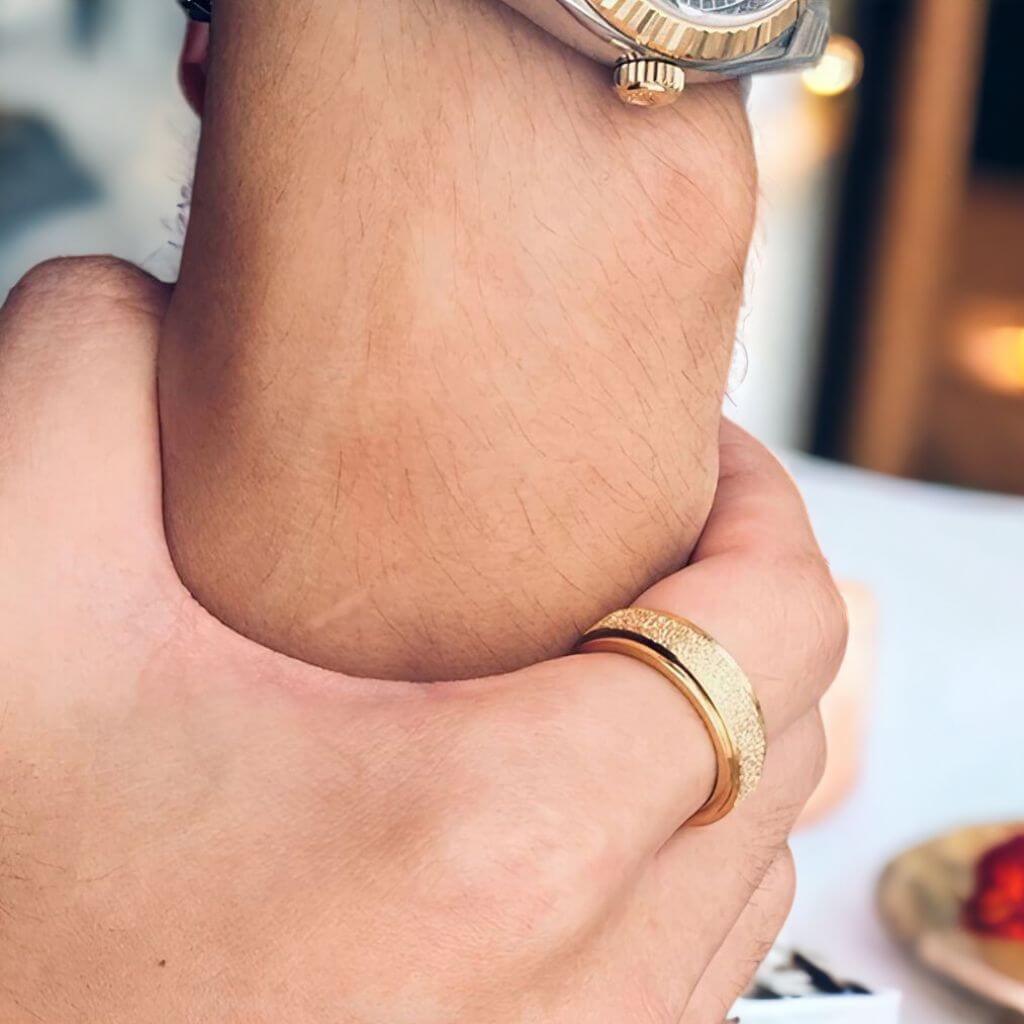 Man&#39;s hand wearing a gold spinning ring on the index finger close up
