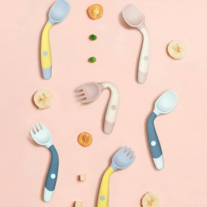 Multi colored bendable handle spoons and forks, fruits on pink background