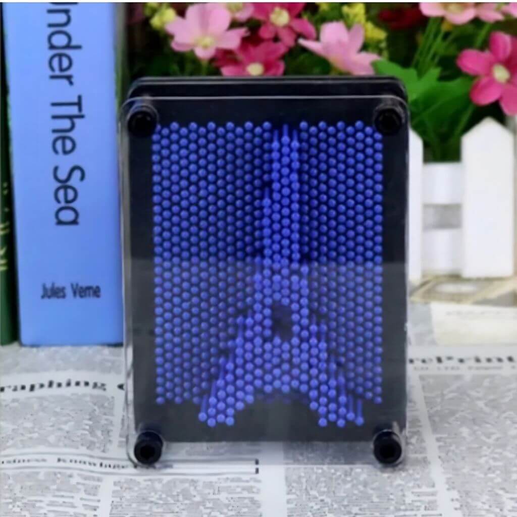 Pin art 3D toy next to a book