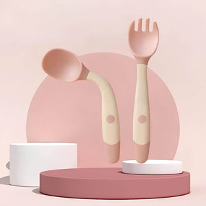 Pink curved handle baby spoon and fork on a background with geometric shapes