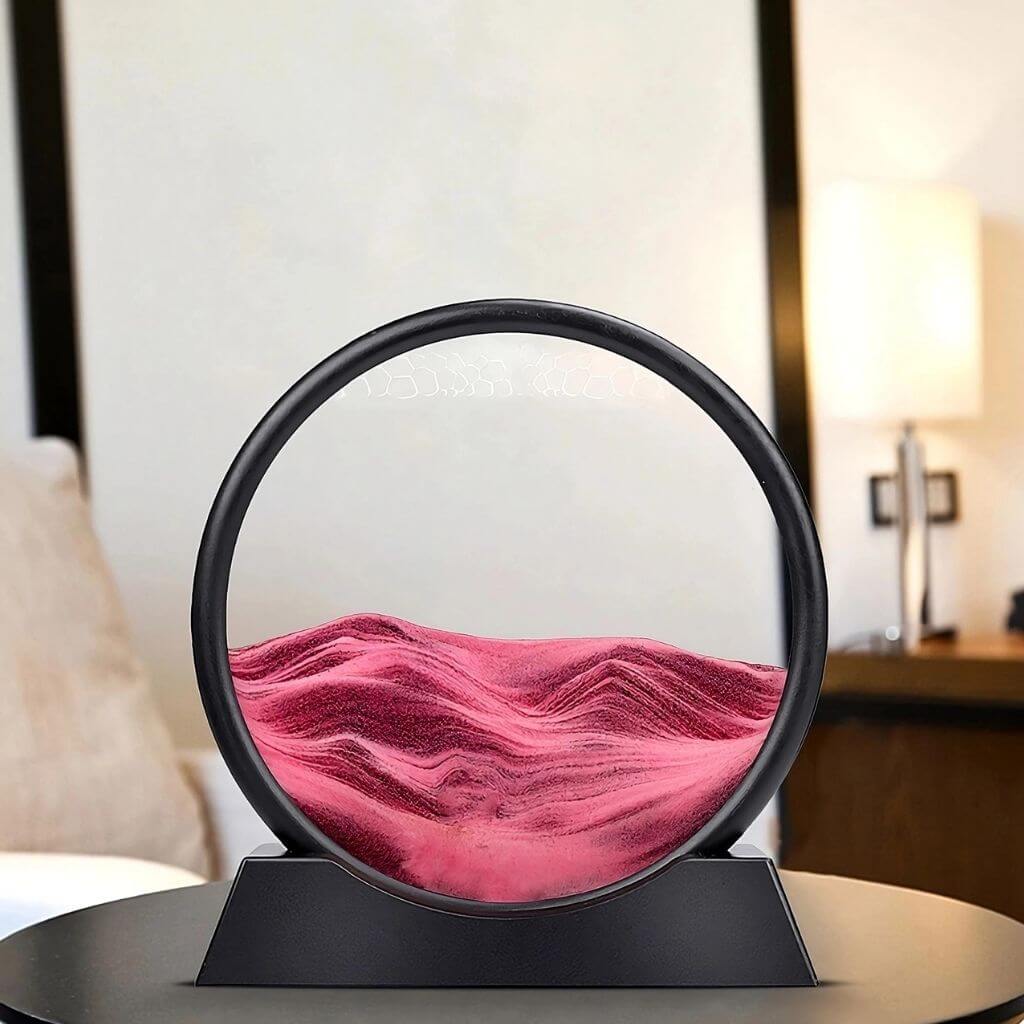 Pink sand art sandscapes on a black table and blurry background