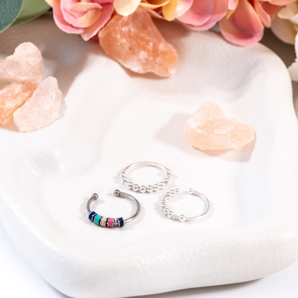 Serenity set bundle of 3 silver worry rings on a white plate with pink flowers in background