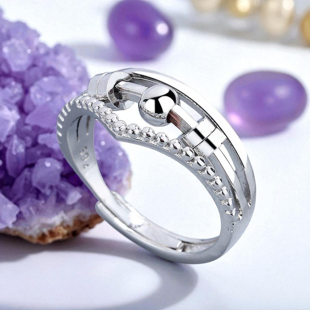 Silver fidget ring for anxiety with purple gemstones in the background