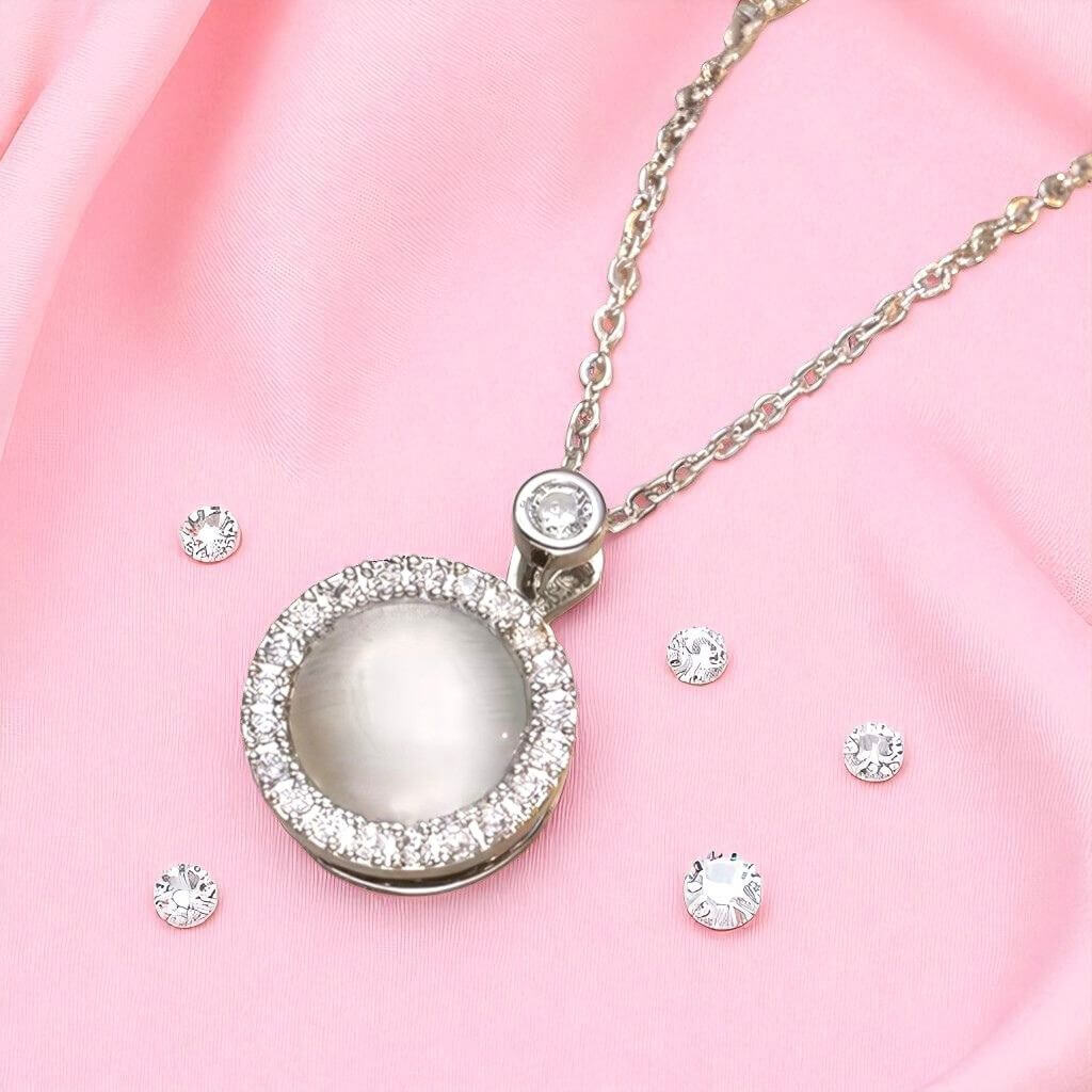 Silver necklace with a round pendant on a pink fabric background