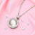 Silver necklace with a round pendant on a pink fabric background