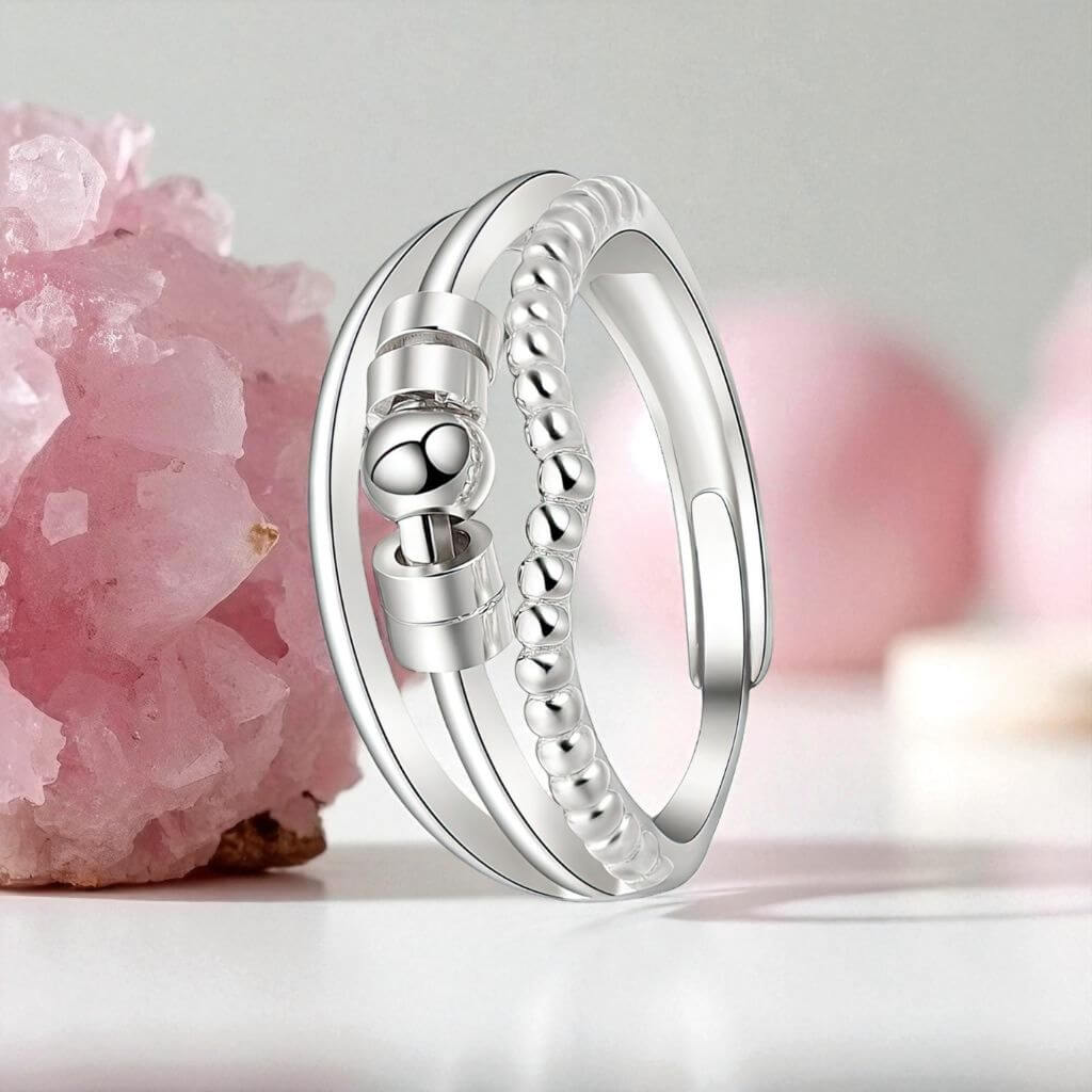 Silver ring  for anxiety with beaded design next to a pink quartz crystal