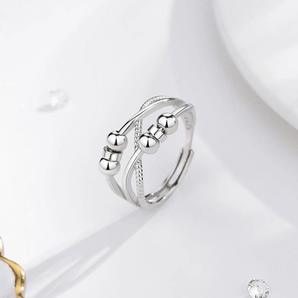 Silver triple band cross over ring for fidgeting next to a white plate