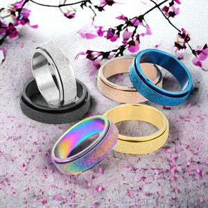 Six fidget rings on a grey surface with a cherry blossoms in background