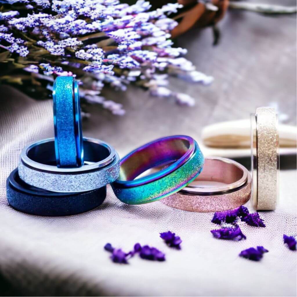 Six multi coloured fidget rings made of stainless steel on white background
