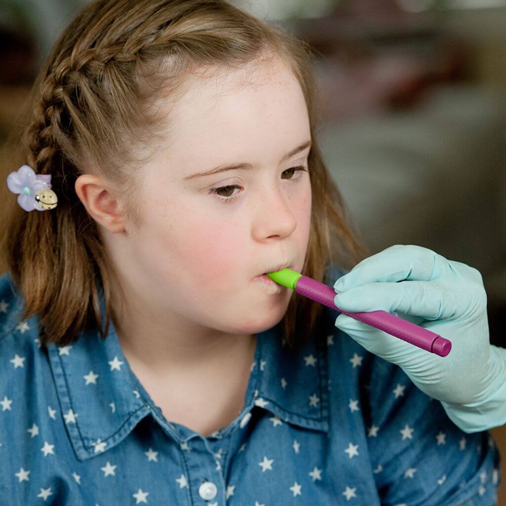 Speech therapist&#39;s hand holding a Ark Therapeutic Z-Vibe with a Bite-n-Chew tip in a girl&#39;s mouth