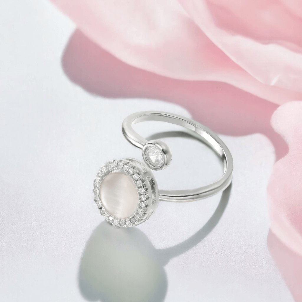 Spinning ring sterling silver on a white surface with pink fabric in background