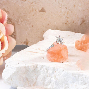 Sun ring with spinning top on Himalayan salt next to a pink flower