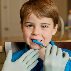 Therapist's hand holding Ark Z-Vibe soft brush tip on a boy's teeth