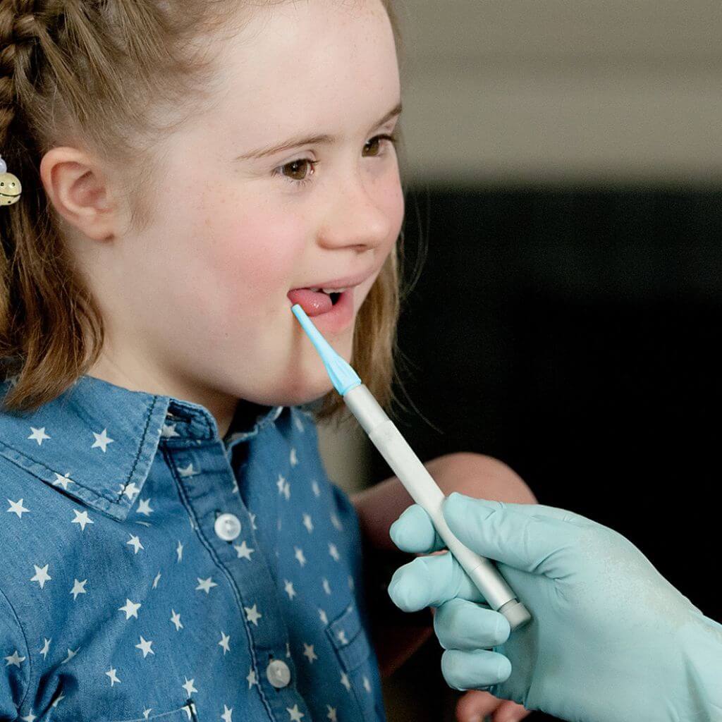 Therapist holding Ark Therapeutic Z-Vibe with a fine tip next to an autistic girl's mouth