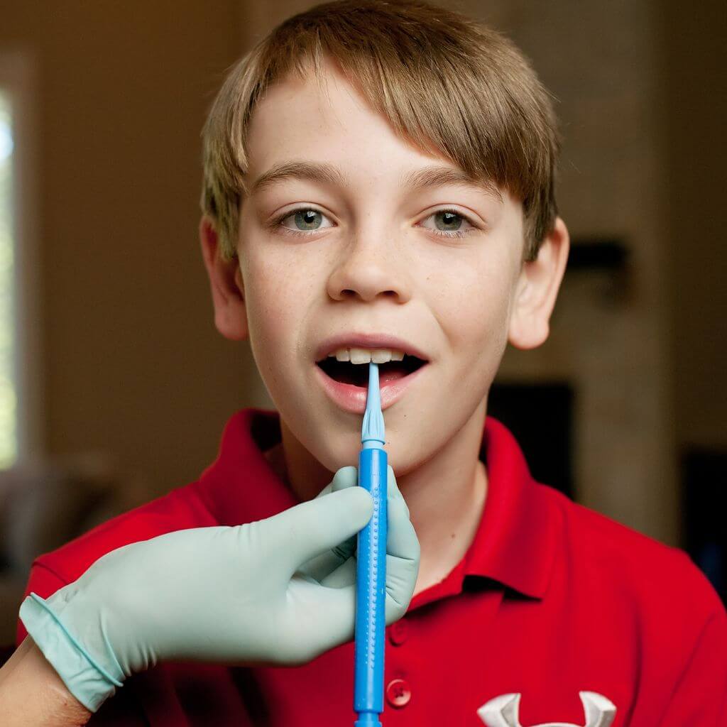 Therapist holding Ark&#39;s Z-Vibe with a fine tip on a boy&#39;s teeth