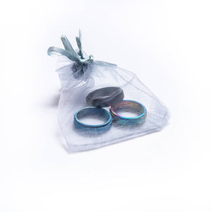 Three spinner rings in a grey organza bag on white background