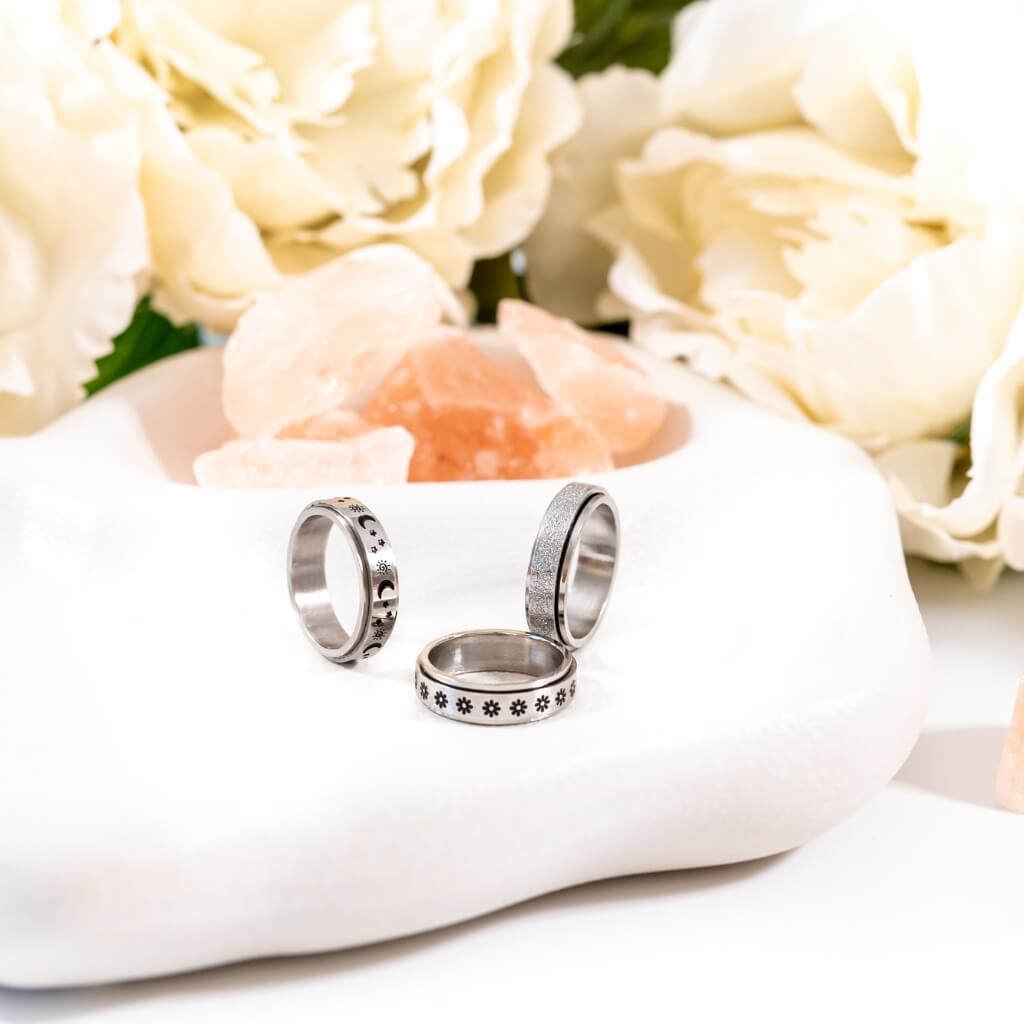 3 stainless steel band spinner rings on a white plate close up