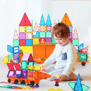 Toddler boy playing with magnetic tiles on the floor with a castle in the background