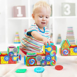 Toddler boy playing with magnetic toys with gears on the floor