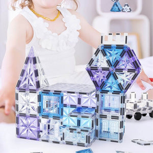 Toddler girl building a castle of magnetic tiles with frozen theme on the floor