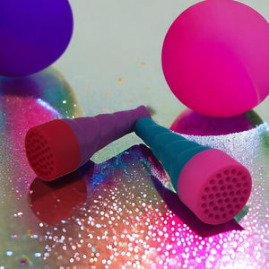 Touchable bubbles blowers on a sparkly surface with balloons in background