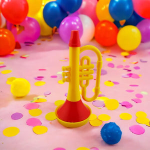 Trumpet bubble blower on a pink surface with confetti