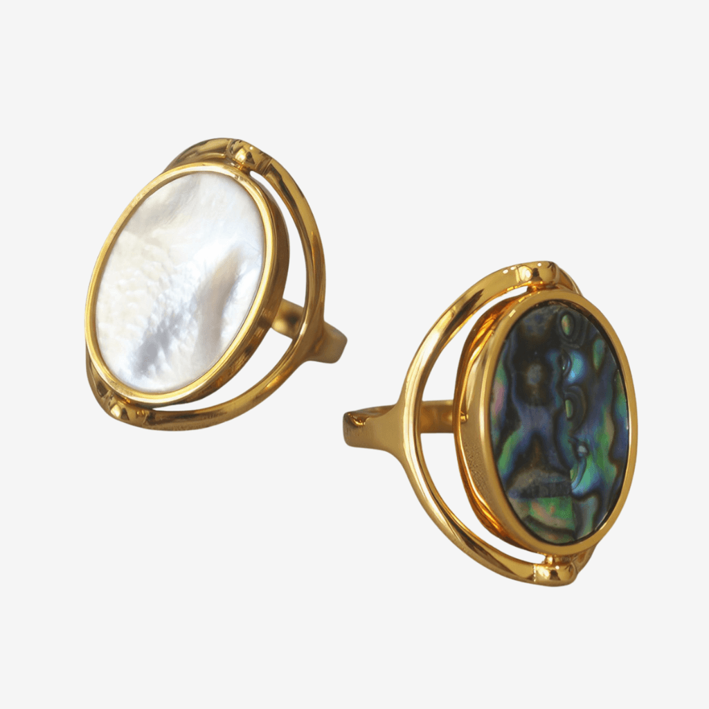 Two gold abalone rotating rings on grey background