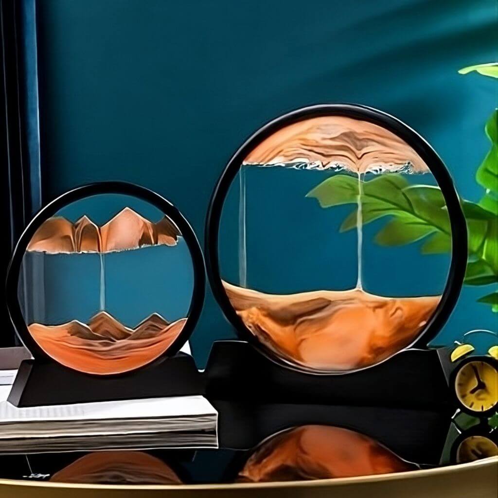 Two orange sand art sandscapes on a mirror like table and teal background