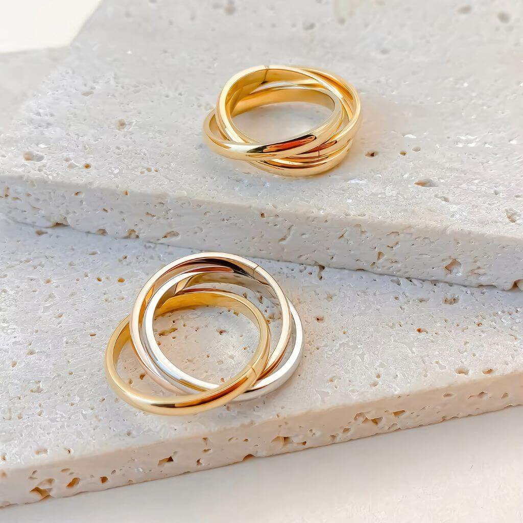 Two stainless steel fidget rings on a textured beige surface