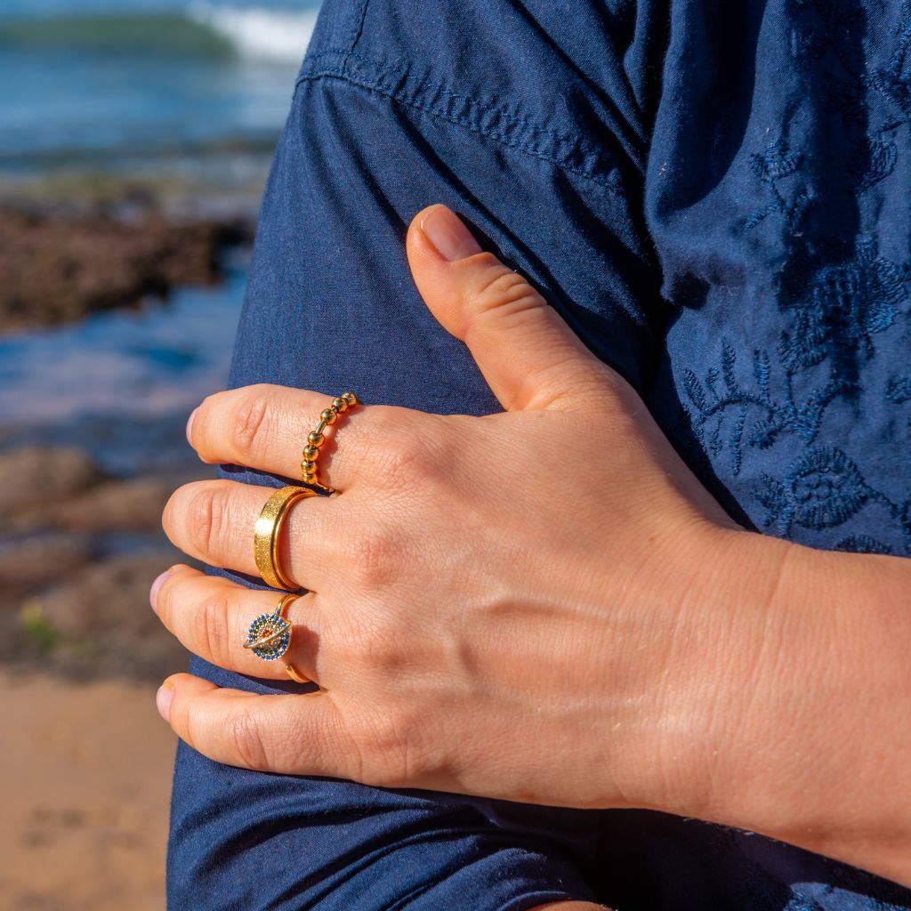 Woman in blue shirt holding her arm wearing three gold spinner rings
