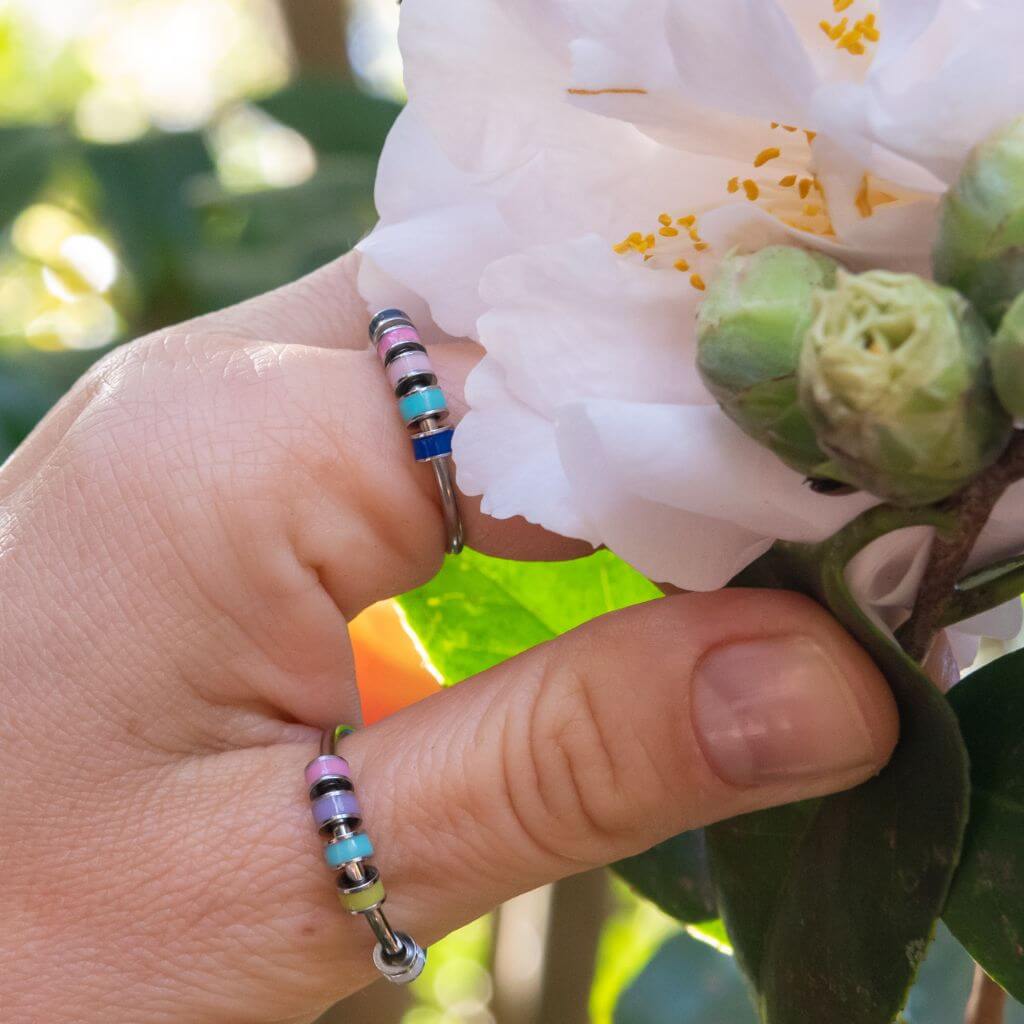 Stainless steel adjustable fidget rings with enamel beads blue and pink on white background