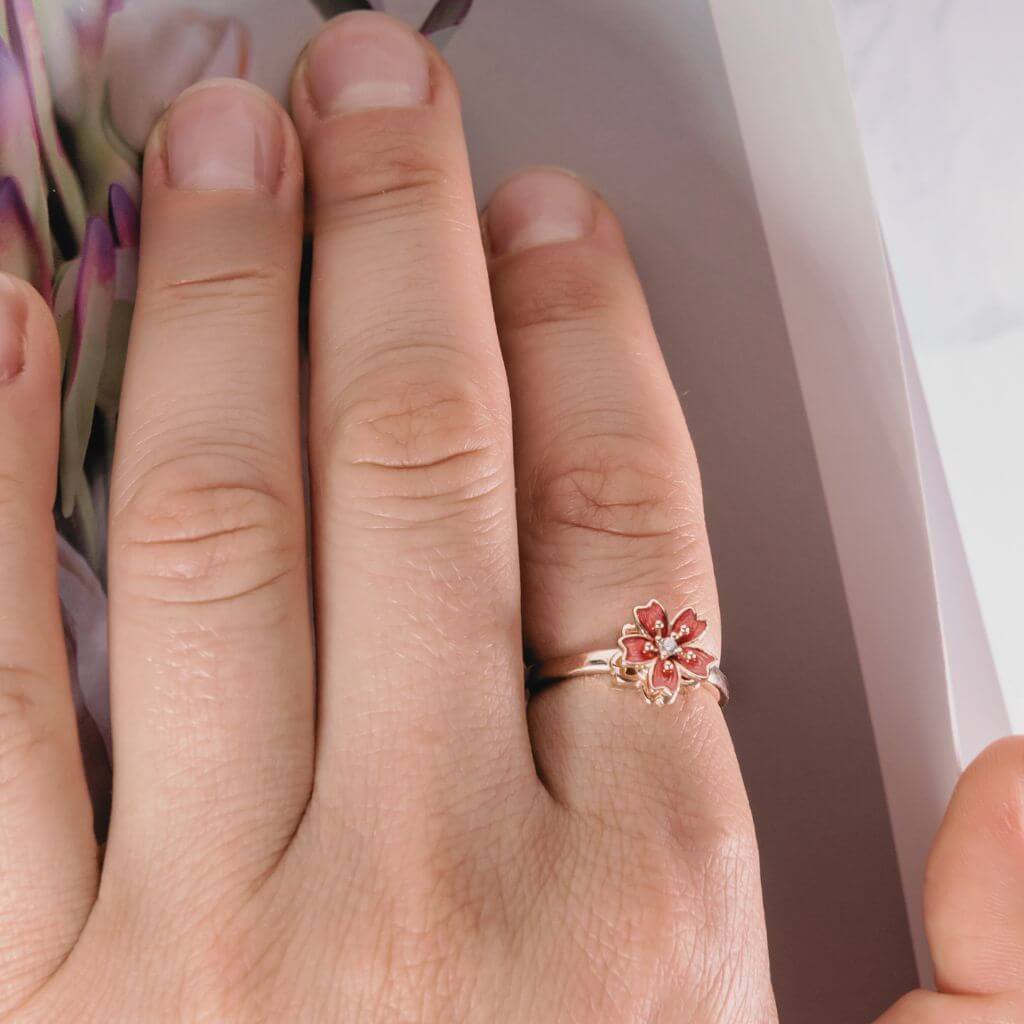 Woman&#39;s hand wearing a flower spinning ring on the index finger next to a magazine cover