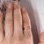 Woman's hand wearing a flower spinning ring on the index finger next to a magazine cover
