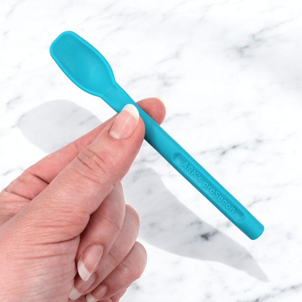 Woman's hand holding an Ark textured prospoon teal