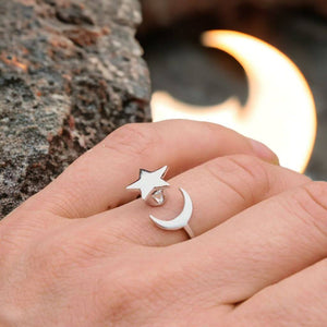 Woman's hand next to a rock  wearing moon and star anxiety ring with a moon shaped light on background