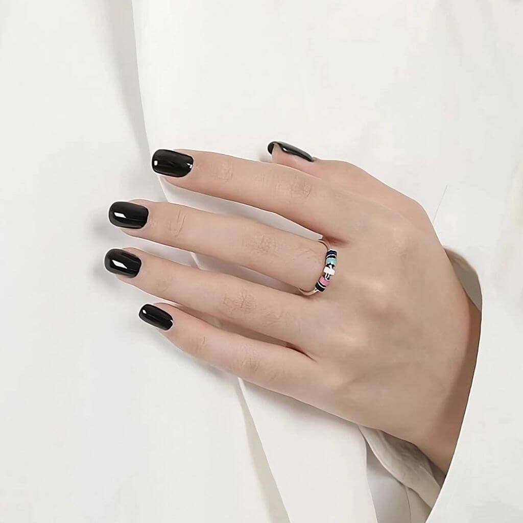 Woman&#39;s hand on white shirt wearing an adjustable spinning ring with enamel beads