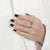 Woman's hand on white shirt wearing an adjustable spinning ring with enamel beads