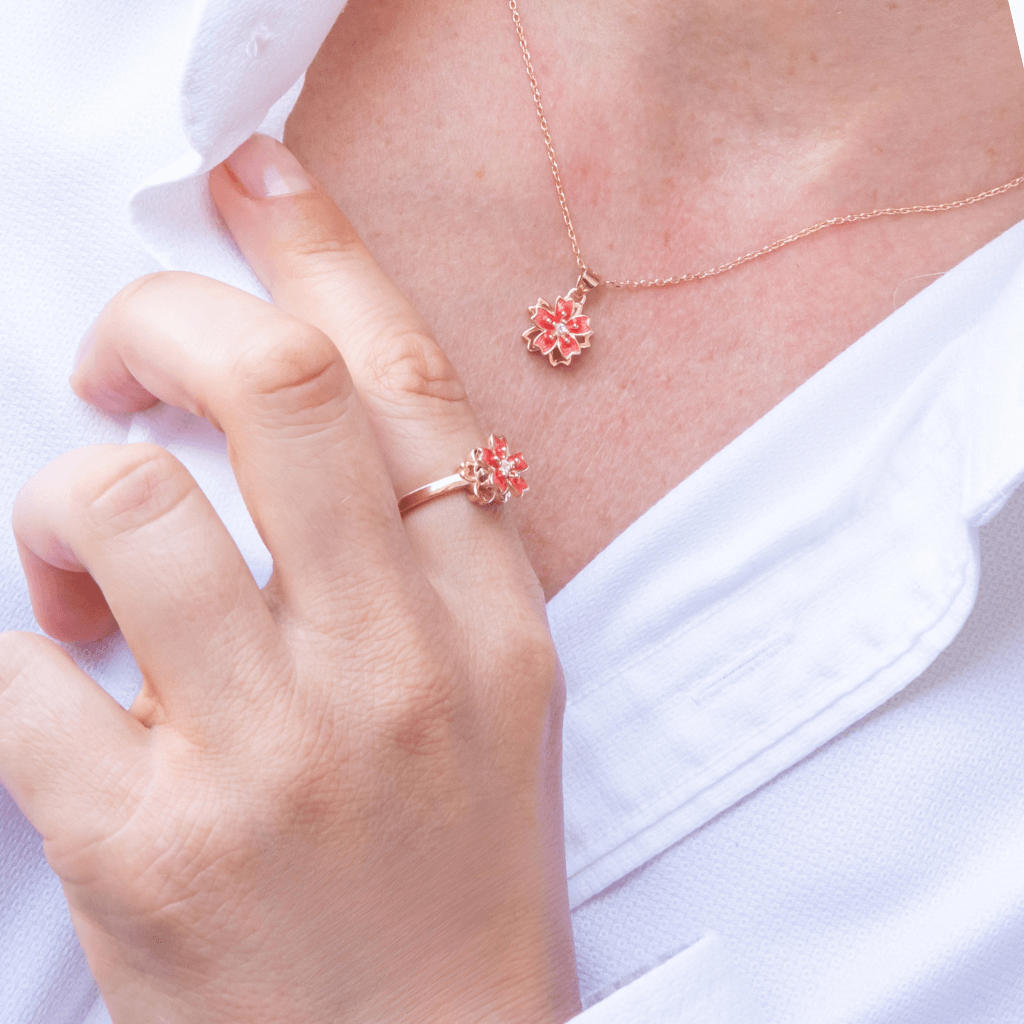 Woman in white shirt wearing an anxiety jewellery set ring and necklace with cherry blossom top