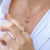 Roman in white shirt wearing a fidget necklace and a ring with flower top