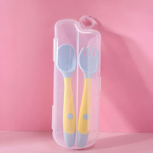 Yellow toddler utensils in a travel case on pink background