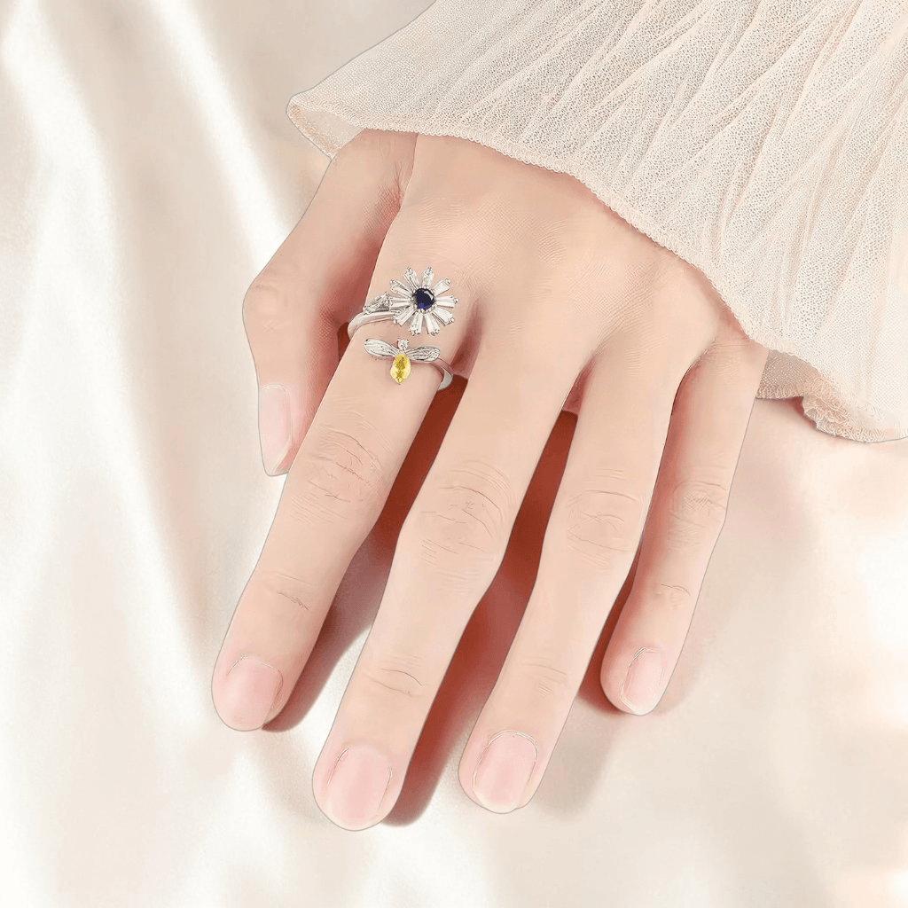 Hand wearing rhodium plated 925 silver daisy spinner fidget ring on cream silk background