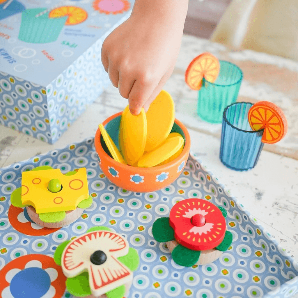 Child playing with Djeco Mia and Leo appetizer wooden play food set serving snacks and assembling toppings