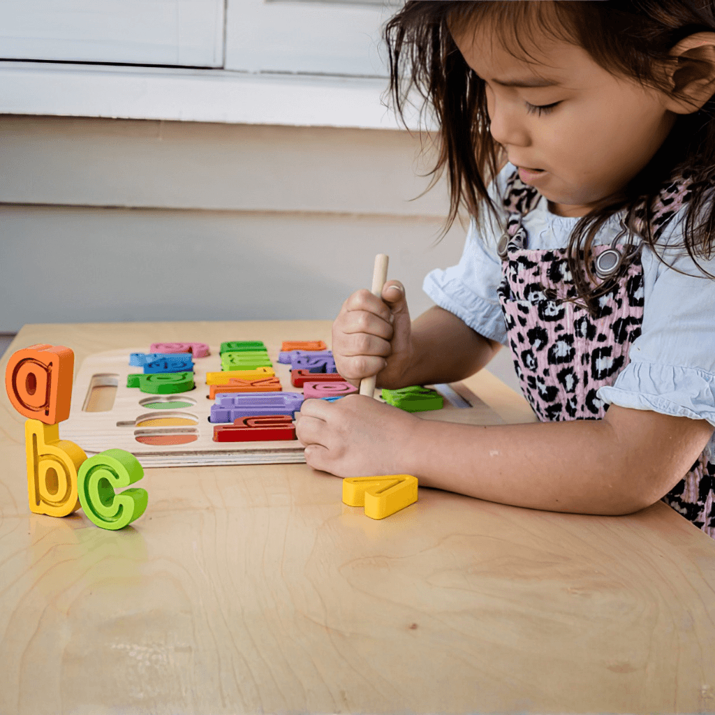 Child using magnetic lowercase alphabet trace puzzle with stylus to practice letter formation and fine motor skills