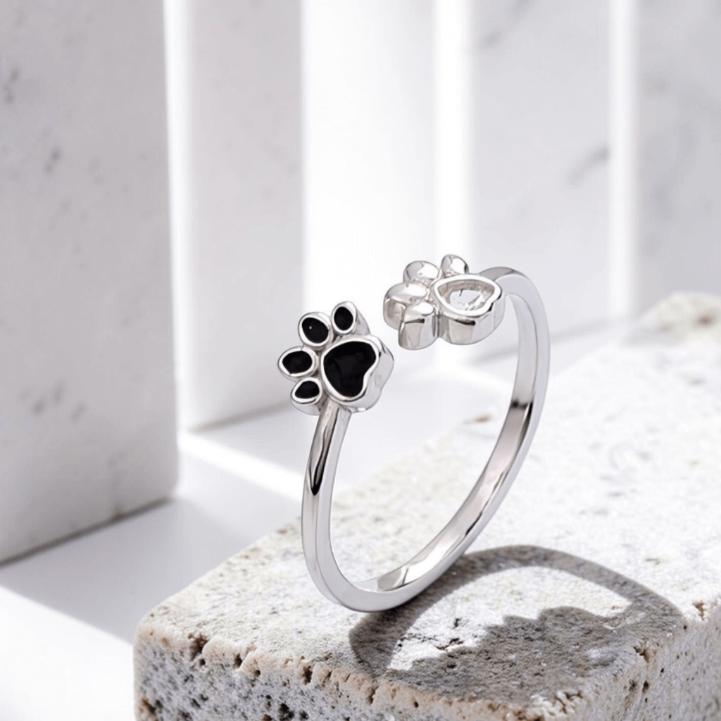 Silver paw print ring on a light stone surface with a neutral background
