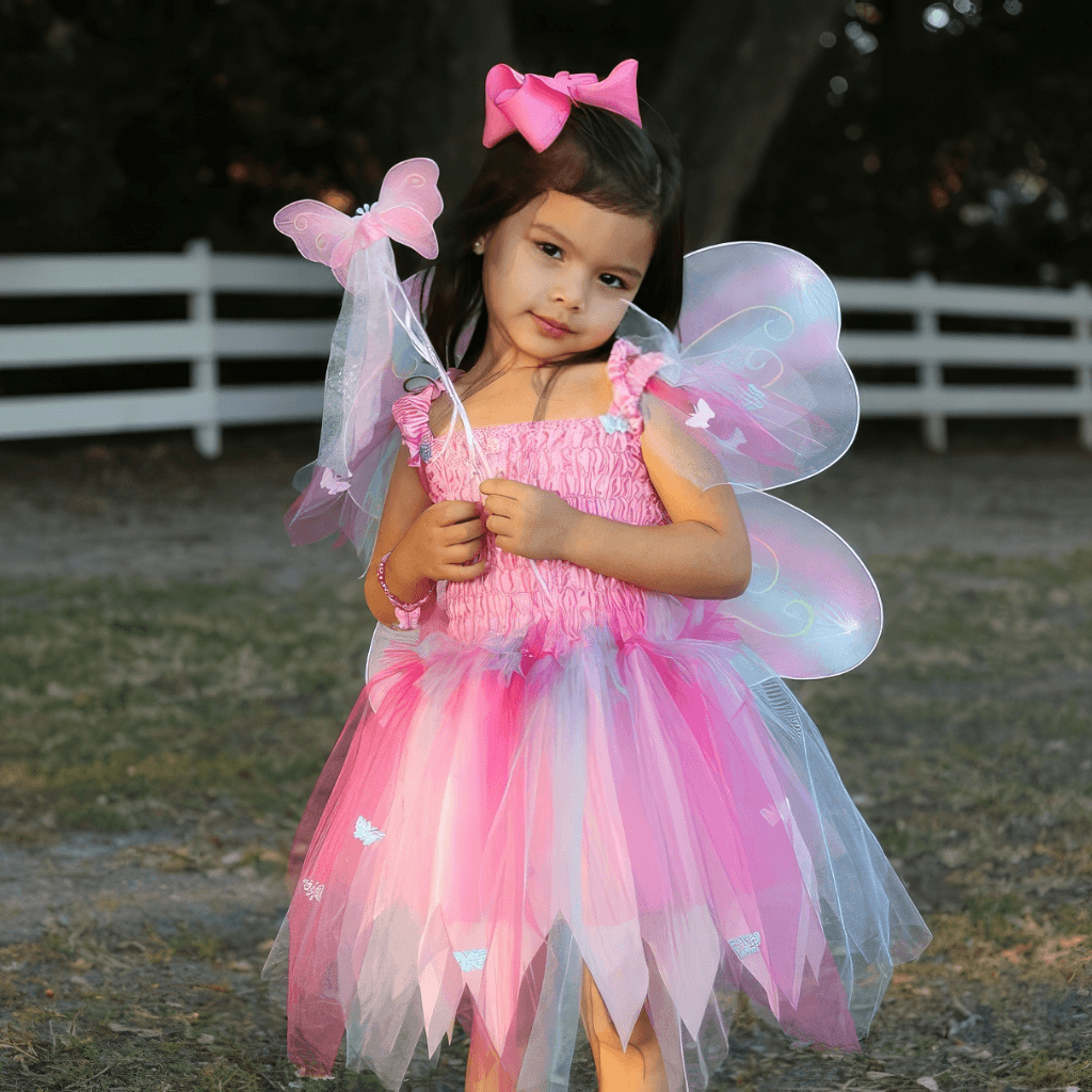 Girl wearing pink butterfly dress up costume with wings and wand outdoors