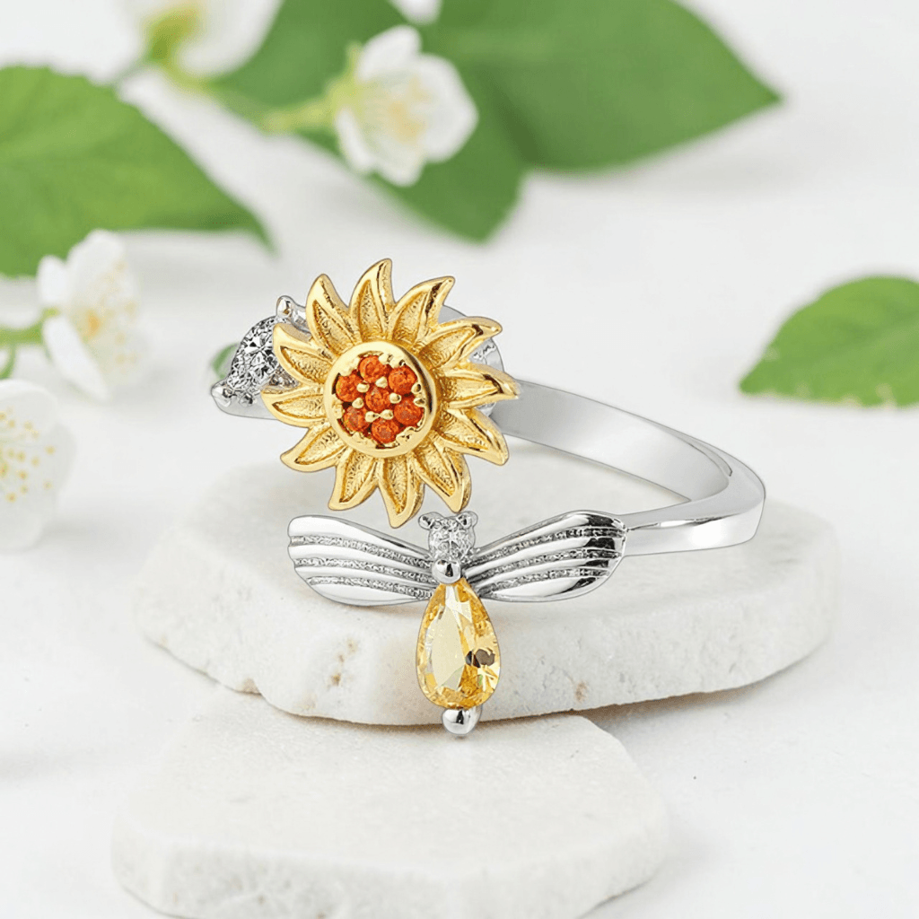 Gold sunflower and silver bee fidget spinner ring with amber cubic zirconia on white stone with white jasmine flowers