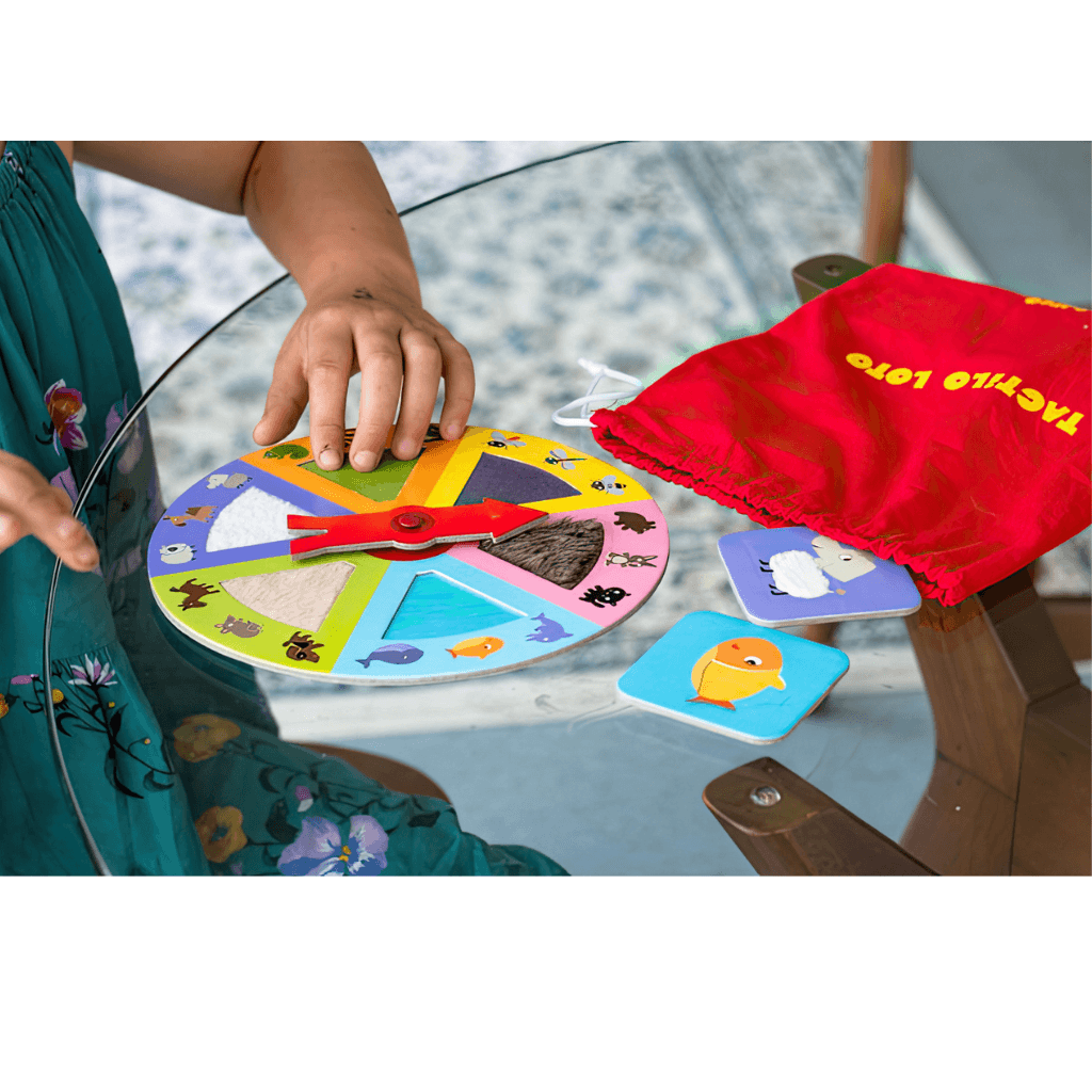 Child hands interacting with Tactilo Loto animal board game spinner and matching pieces