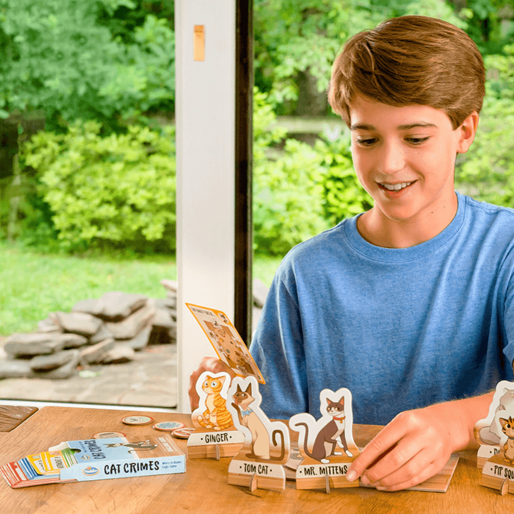 Boy solving ThinkFun Cat Crimes logic puzzle using challenge card and cat suspect tokens