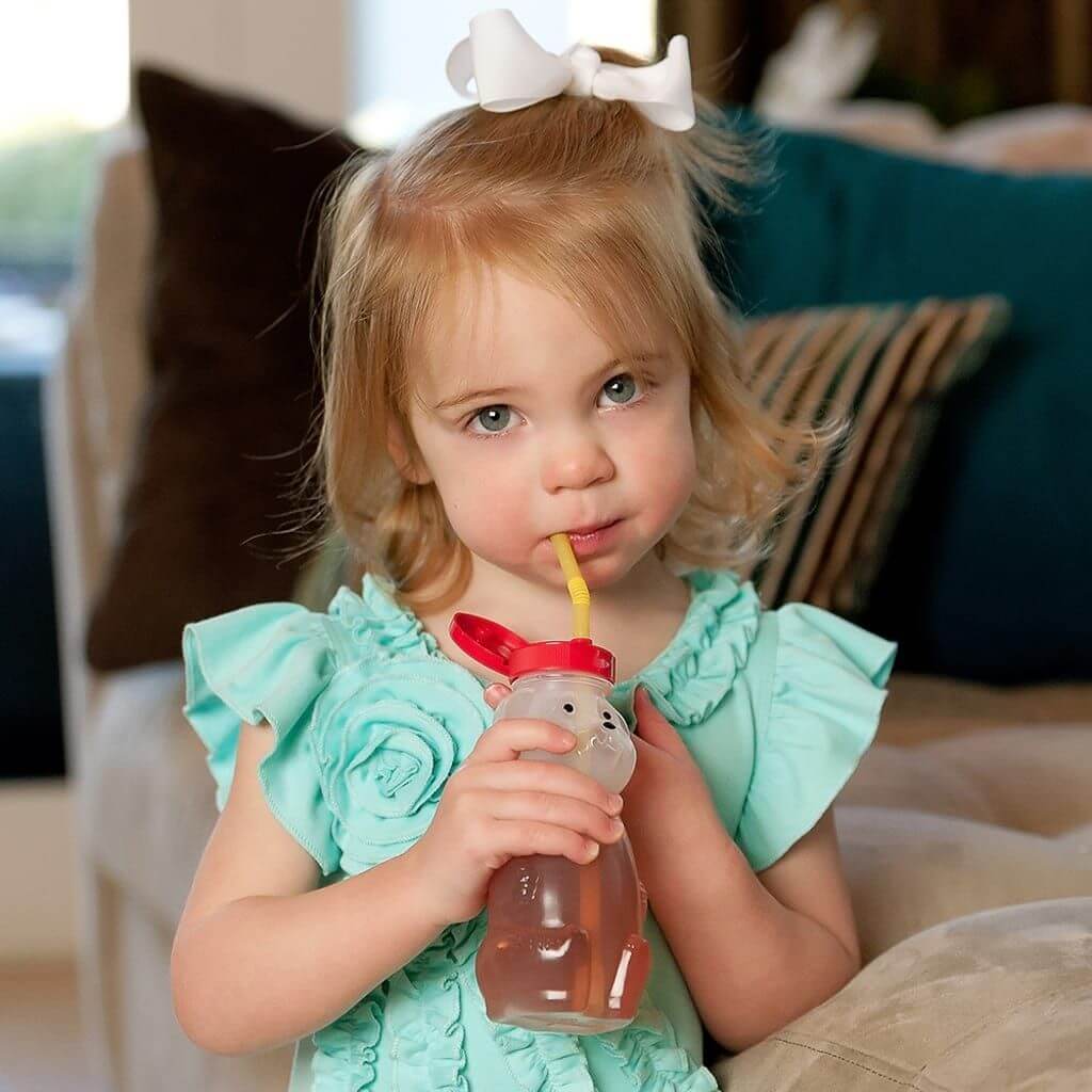 Cucasian girl smiling while drinking from Ark bear bottle