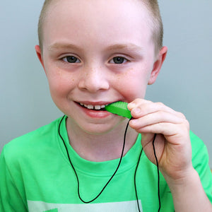Boy chewing on a lime green chew necklace from Ark Therapeutic